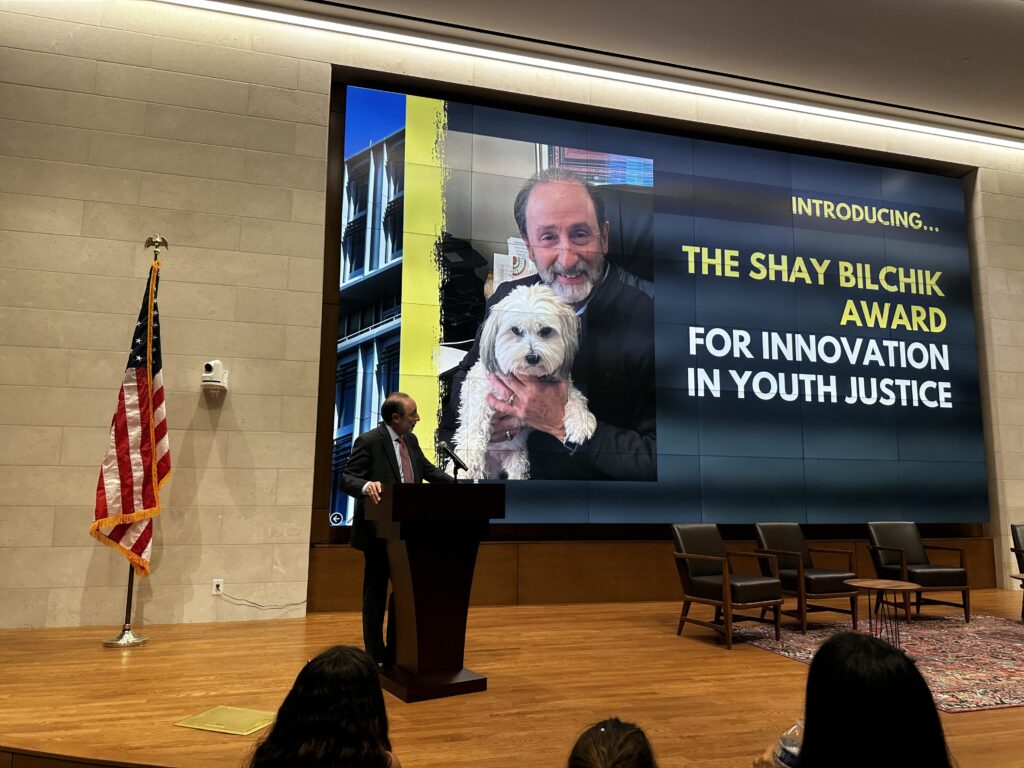Shay Accepting Award on large stage, looking back at big screen announcing Innovation Award with him and his dog on it.