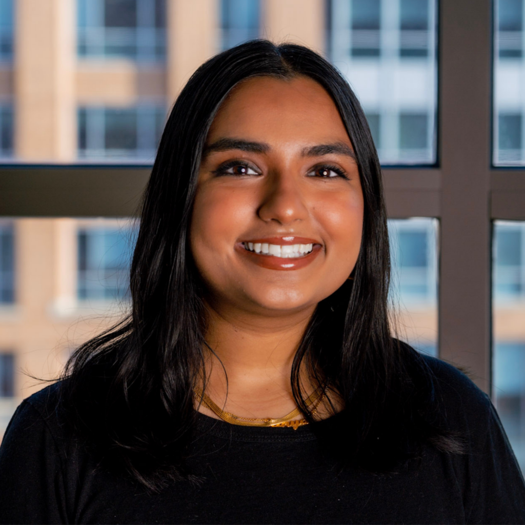 Anya smiling in front of window with DC buildings in background