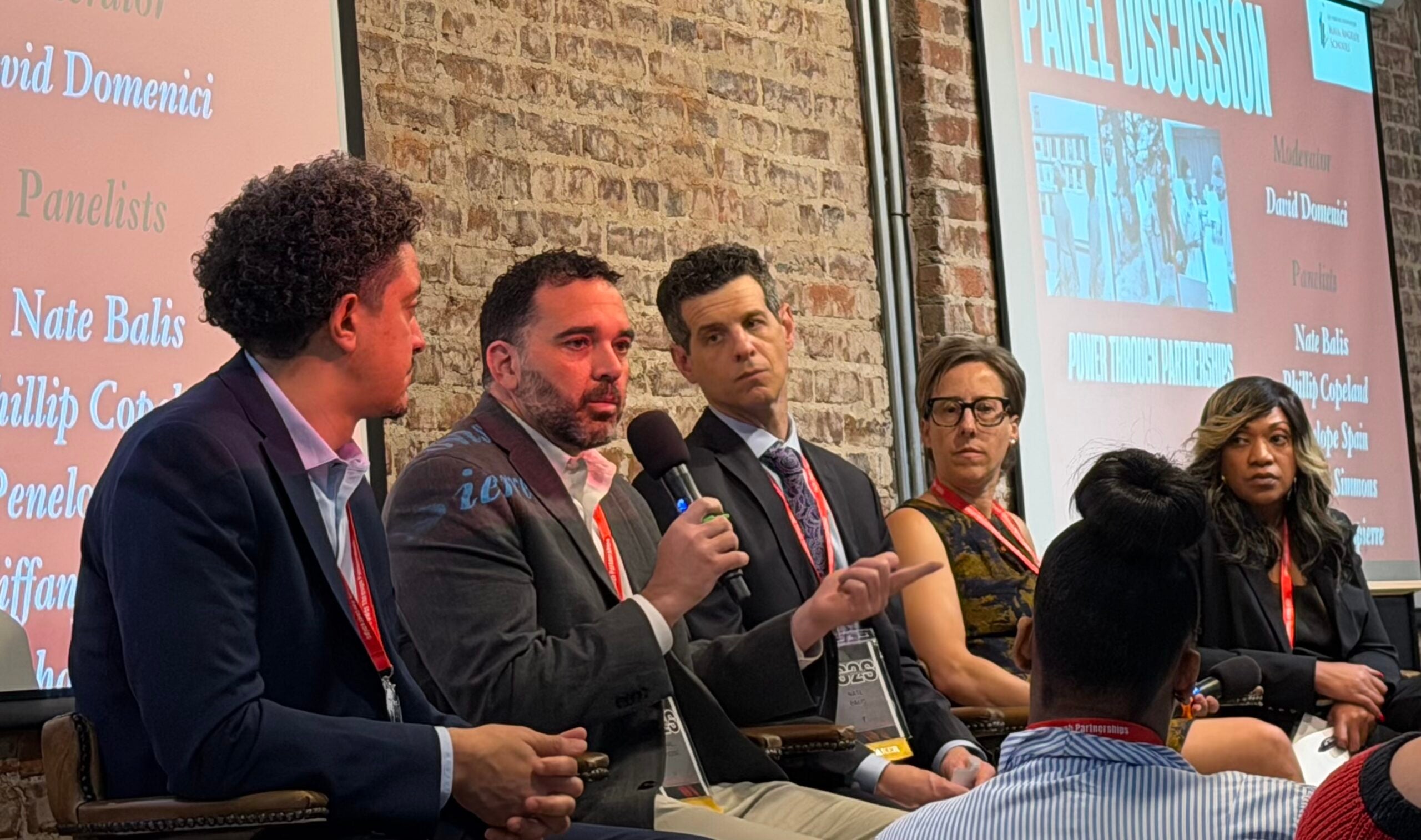 Panel of speakers, with Michael Umpierre holding a microphone