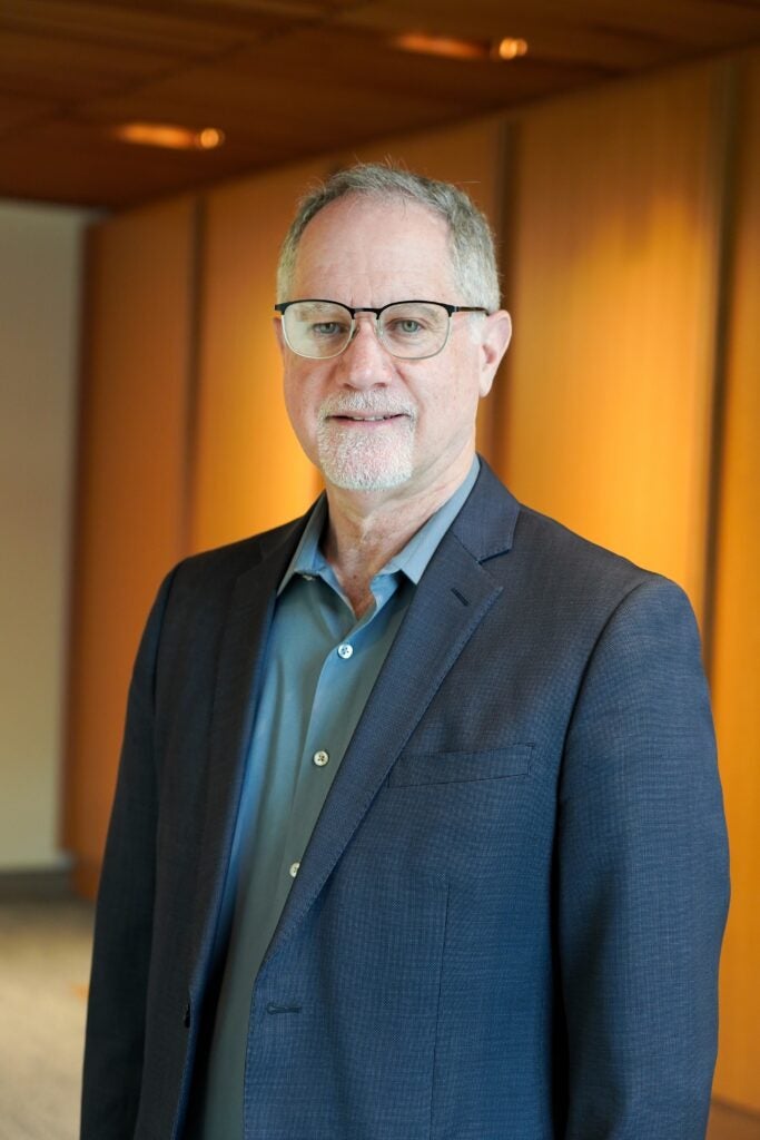 Marc Schindler smiling in suit in warm office setting