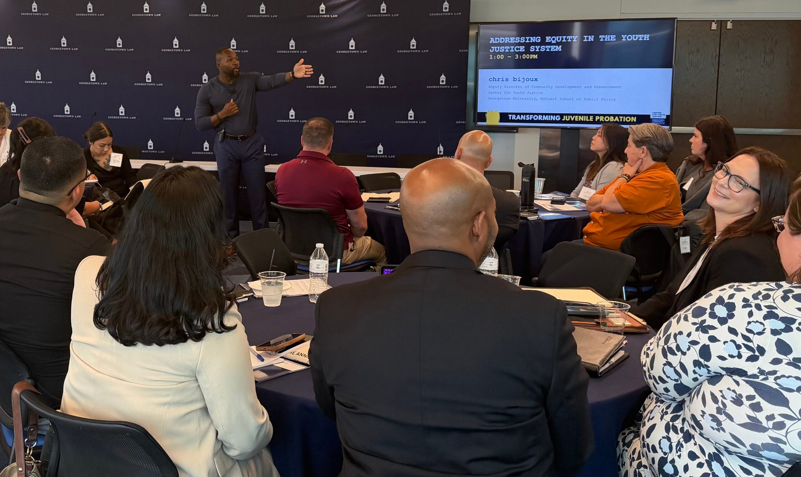 chris bijoux speaking in front of a Georgetown Law background in a room full of Certificate Program participants