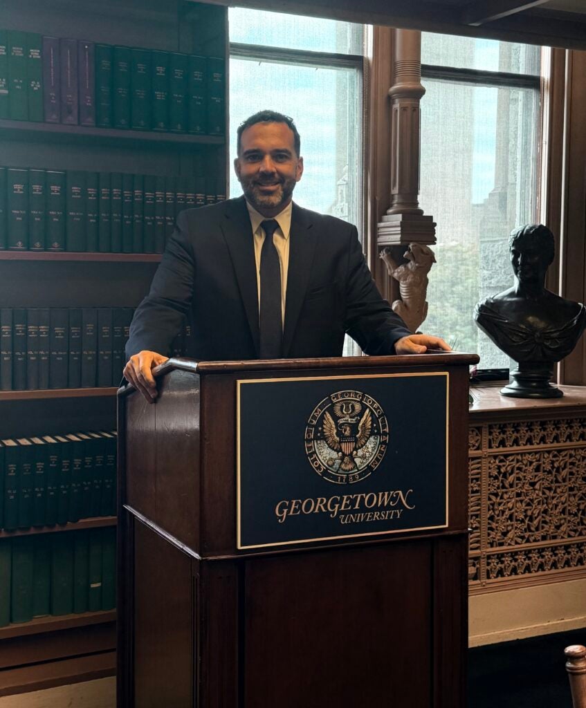 Michael Umpierre speaking at a podium in a distinguish room full of Certificate Program participants.
