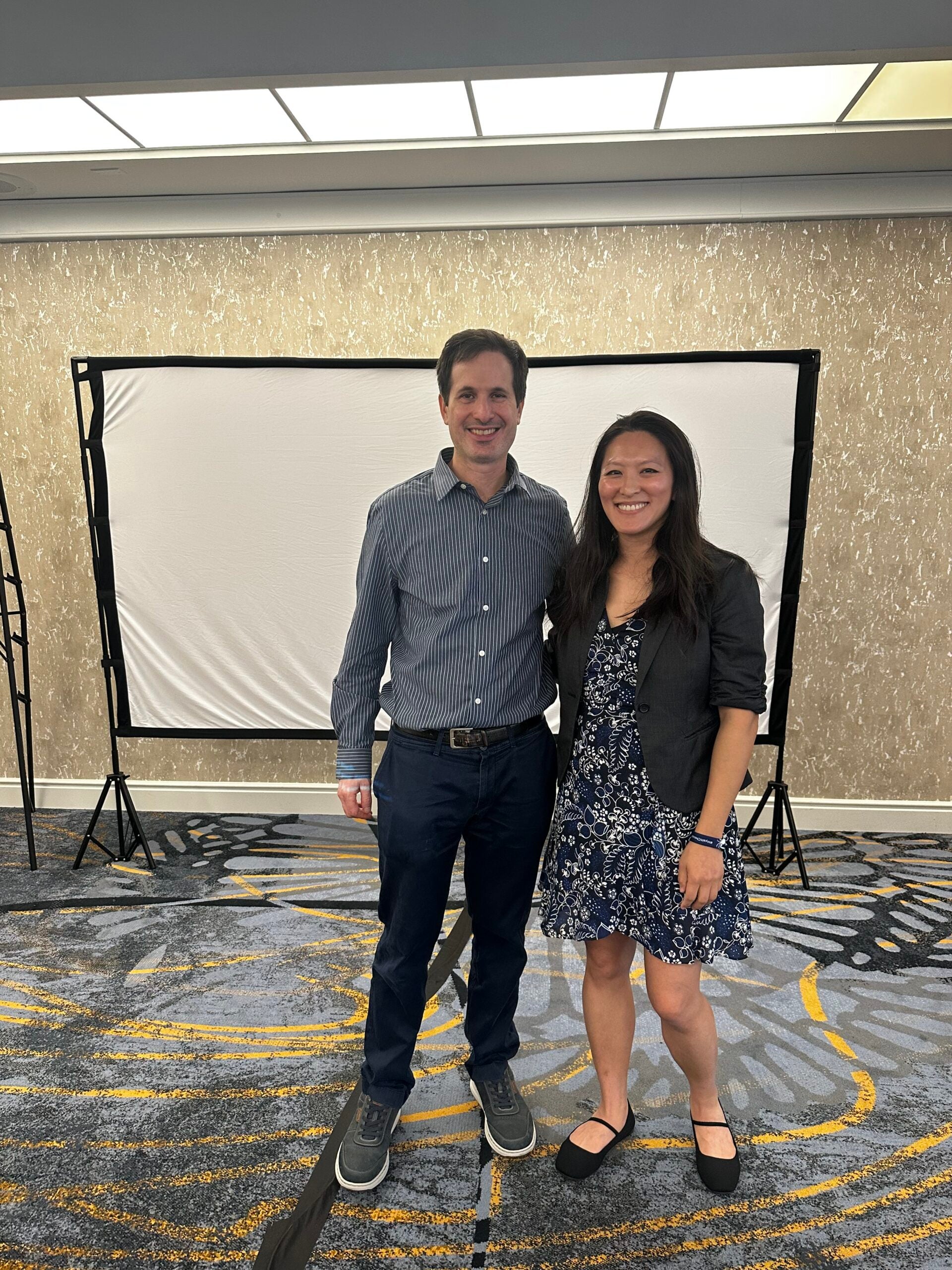 Amber Farn and Ian Augarten standing in front of a projector screen