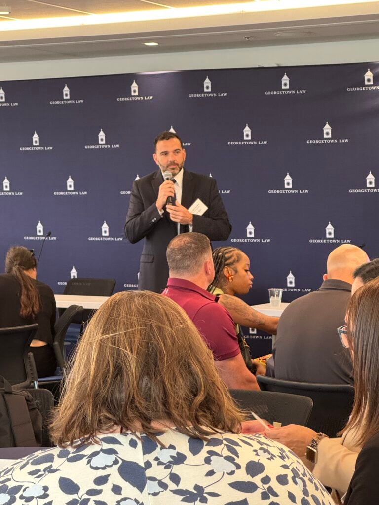 chris bijoux speaking in front of a Georgetown Law background in a room full of Certificate Program participants