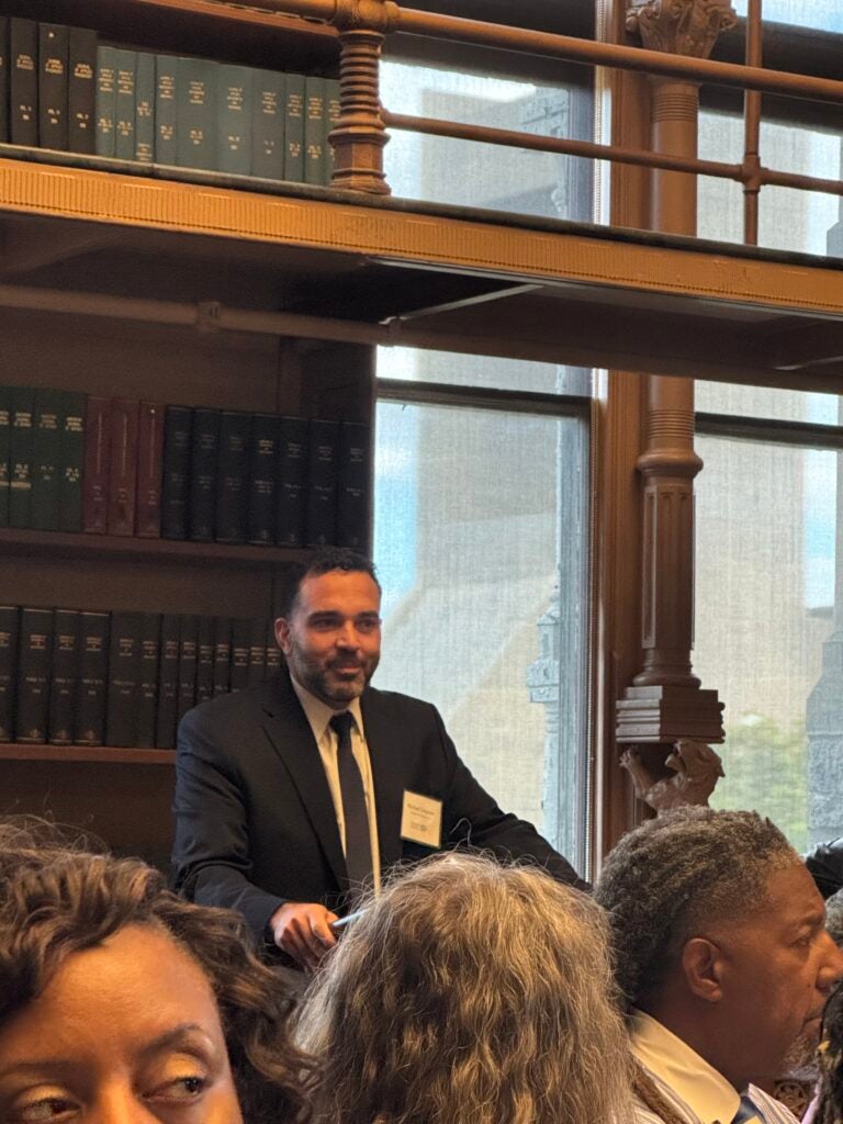 Michael Umpierre speaking at a podium in a distinguish room full of Certificate Program participants.