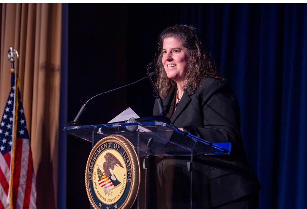 Liz Ryan speaking at DOJ podium