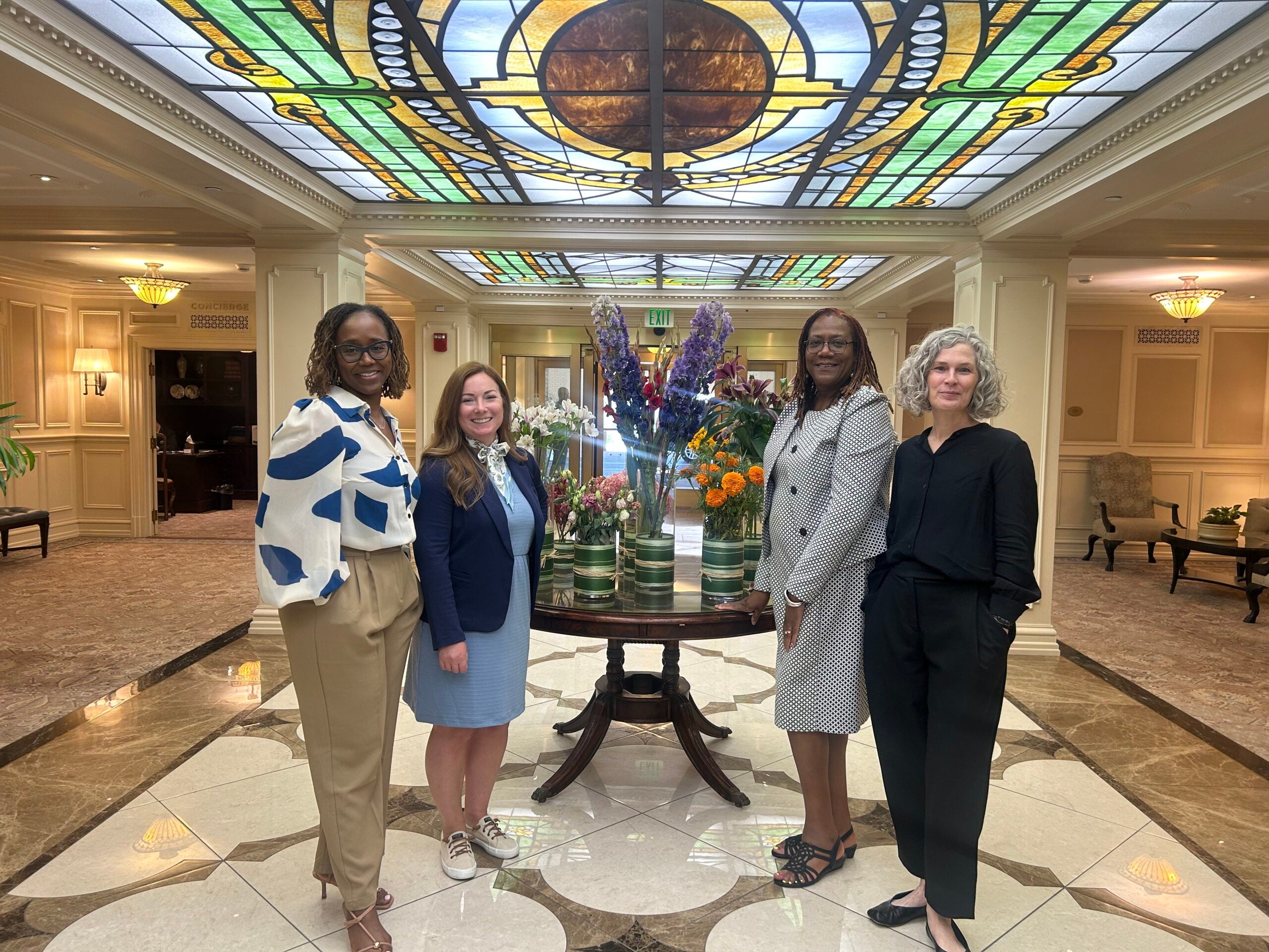 Four women smiling in hotel lobby: Tracy Fehrenbach, Ph.D.; Alexandra M. Miller, Ph.D.; Beverly S. Schulterbrandt, Esquire; Macon C. Stewart, MSW
